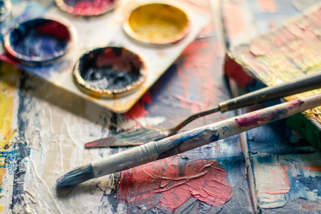 Vibrant close-up of paintbrushes and a palette on a textured canvas showcasing creativity.