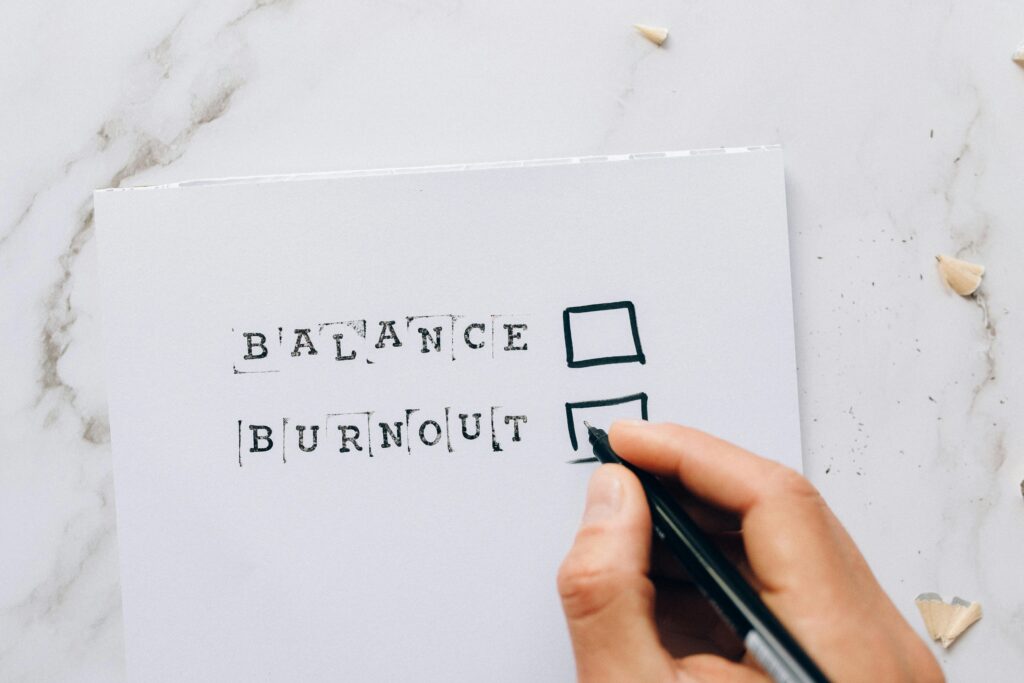 Close-up of a hand hovering over a checklist with options for balance or burnout, symbolizing stress and choice.