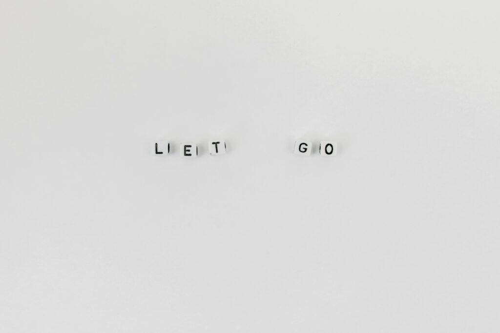 Minimalist composition featuring 'Let Go' spelled with letter dice on a clean white background.